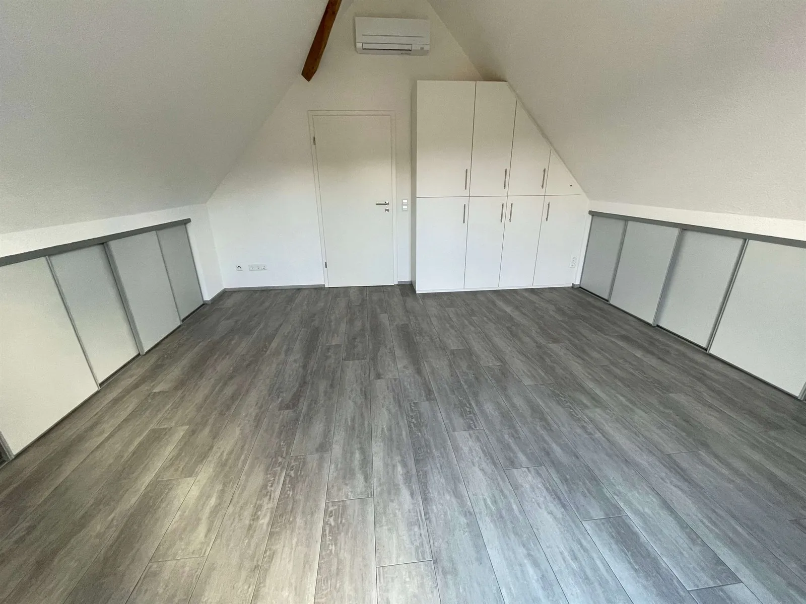 Dachgeschoss mit verkleideten Dachschrägen und grauem Boden